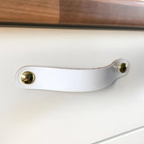 De Tomasso White leren lade trekker van yessential.nl, bevestigd aan een witte lade onder een houten aanrecht, benadrukt de stijlvolle elegantie van witte leren handgrepen in elk interieur.