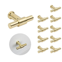 De 10x Cordero Gold Knopenset van yessential.nl heeft moderne, cilindervormige goudkleurige knoppen. Eén knop wordt apart getoond en een andere geïnstalleerd op een witte lade - ideaal voor het upgraden van je keukenkastjes.