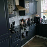 Gouden deurknopjes op een donkere keuken. T-vorm goudkleurige meubelknopjes.