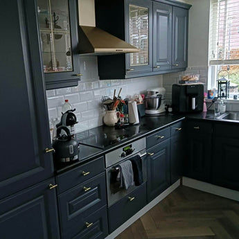 Gouden deurknopjes op een donkere keuken. T-vorm goudkleurige meubelknopjes.