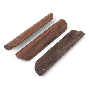 Drie Lucasso Walnut handgrepen van yessential.nl worden getoond op een witte achtergrond, met een gladde afwerking, unieke randvormen en twee stervormige schroefgaten - ideaal voor een natuurlijke inrichting.
