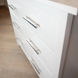 Close-up van het Marano RVS dressoir van yessential.nl, met drie lades met strakke, minimalistische zilveren handgrepen, staande op een lichte houten vloer.