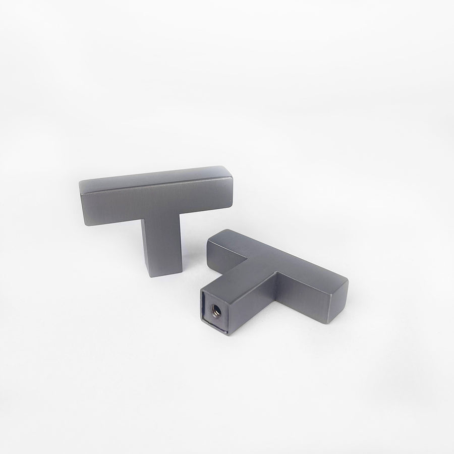 Twee Vigio Gunmetal Knobs van yessential.nl worden getoond op een witte achtergrond - een rechtop en een plat liggend, waardoor de schroefdraad zichtbaar wordt. Beide hebben een gladde, matte afwerking die hun moderne design benadrukt.