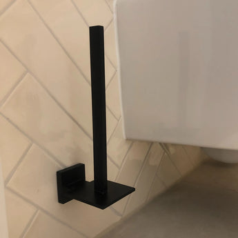 De Moreno Black WC-set van yessential.nl, in stijlvol mat zwart, wordt aan de wand gemonteerd in een betegelde badkamer. Een perfecte, elegante upgrade voor je badkameraccessoires of toiletaccessoires. Toilet gedeeltelijk zichtbaar; toiletrol niet inbegrepen.