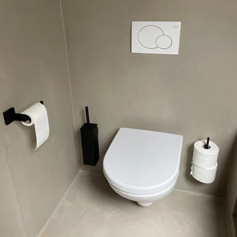 Een toilet in de badkamer met de Alessino Black matzwarte toiletborstel en houder van yessential.nl naast de wc voor een stijlvolle en hygiënische touch.