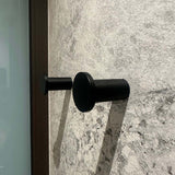 Vier zwarte cilindrische Carreno handdoekhaakjes van yessential.nl, gemaakt van roestvrij staal, zijn gemonteerd op een gestructureerde wand van grijze steen - een elegante en moderne badkameraccessoire.