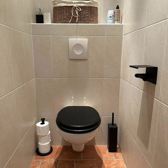 Een kleine, moderne badkamer met beige betegelde muren en een terracotta vloer is voorzien van een wandcloset met een zwarte zitting, aangevuld met de yessential.nl Lazzo Black WC Set (no-drill), allemaal eenvoudig te installeren zonder boren.