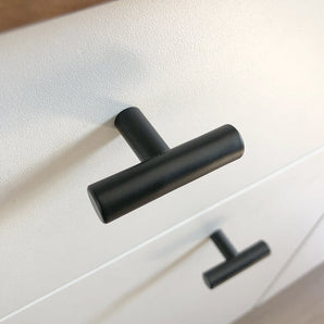 Close-up van een Remo Black knop van yessential.nl op een witte lade, met daaronder nog een identieke knop. De hoek benadrukt het moderne, minimalistische ontwerp van dit strakke beslag.