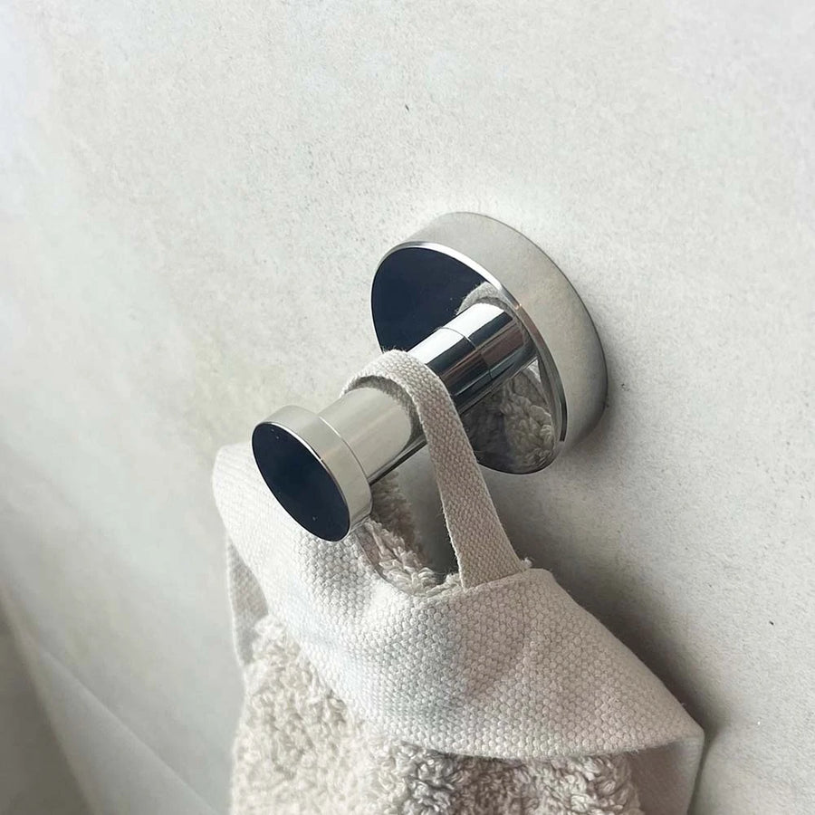 Een beige handdoek hangt aan zijn lus op de Midao Chroom WC-set van yessential.nl, aan de muur bevestigd tegen een lichtgekleurde achtergrond.