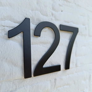 Animo Black 7, 6cm (geen boor) huisnummer van yessential.nl in zwart op een witte bakstenen muur.