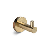 De Justo Gold Hook van yessential.nl is een goudkleurige metalen wandhaak met een ronde basis en cilindrische pin, die een elegante touch toevoegt, weergegeven op een effen witte achtergrond.